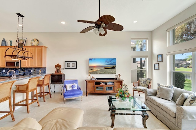 living area with a wealth of natural light, light tile patterned flooring, a high ceiling, and recessed lighting