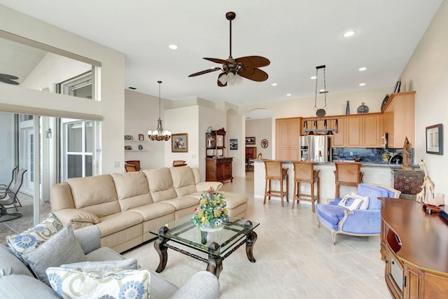 living room with arched walkways, light tile patterned floors, recessed lighting, and ceiling fan with notable chandelier