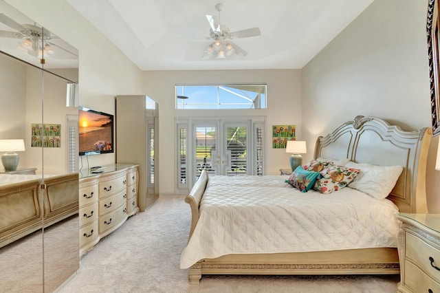 bedroom featuring ceiling fan, light carpet, access to exterior, french doors, and a tray ceiling