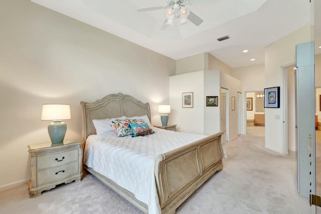 bedroom with ensuite bathroom, recessed lighting, light carpet, visible vents, and a raised ceiling