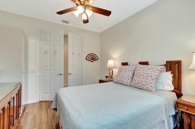 bedroom featuring light wood-style floors, visible vents, baseboards, and a ceiling fan