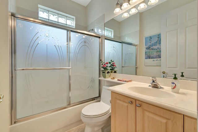 full bath featuring combined bath / shower with glass door, vanity, and toilet