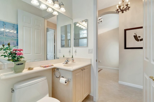 bathroom featuring a notable chandelier, vanity, toilet, and baseboards