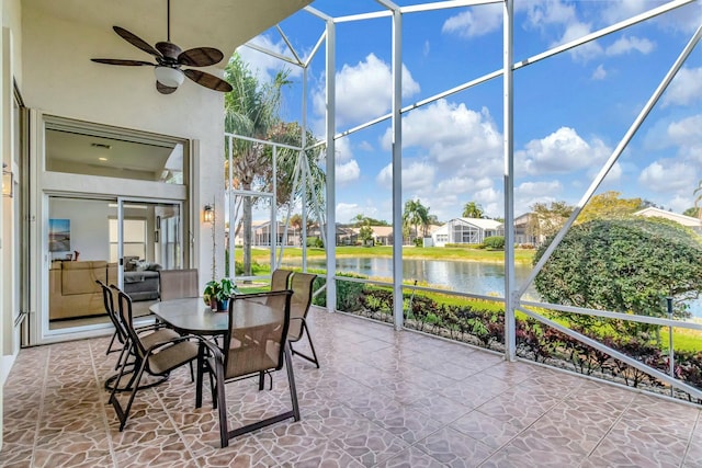 sunroom / solarium featuring a water view and a ceiling fan