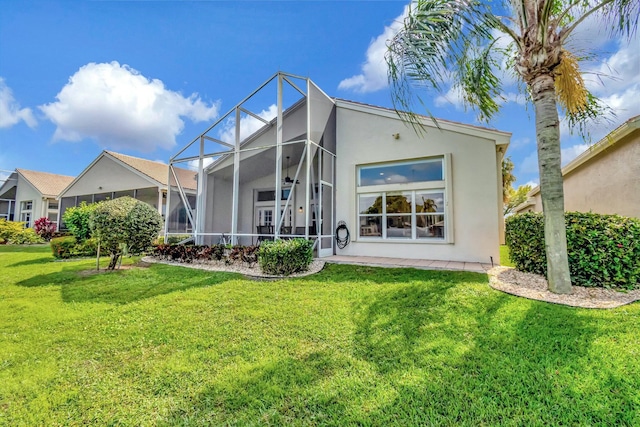 rear view of house featuring a lanai, a lawn, and stucco siding