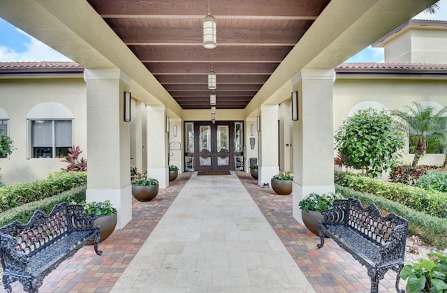 doorway to property featuring a tile roof, french doors, and stucco siding