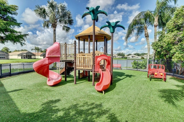 community play area featuring fence and a yard