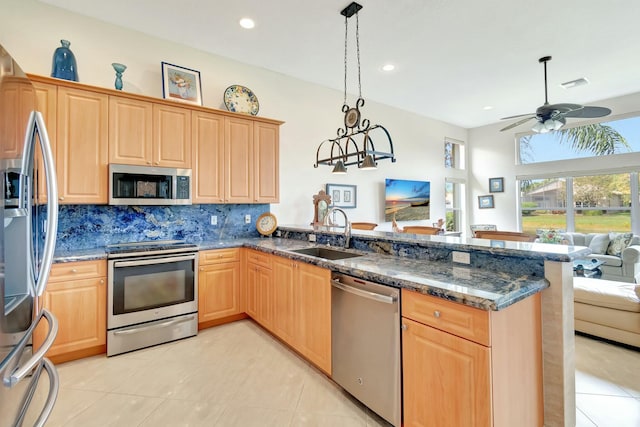 kitchen with visible vents, appliances with stainless steel finishes, open floor plan, a sink, and a peninsula