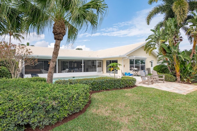 back of property with a patio, a yard, and a sunroom