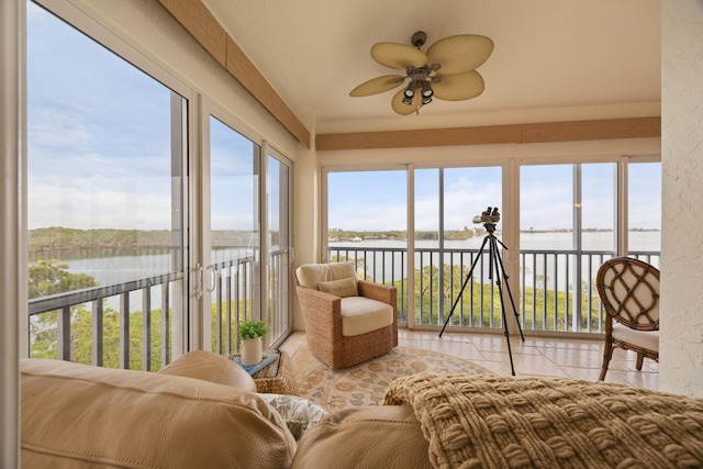 sunroom featuring ceiling fan, a water view, and a healthy amount of sunlight