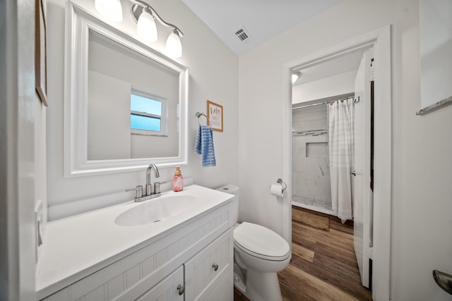 bathroom featuring curtained shower, toilet, wood finished floors, vanity, and visible vents