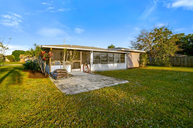 rear view of house featuring a yard, a sunroom, a patio, and fence