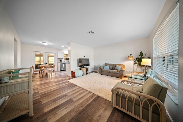 living area with french doors, wood finished floors, and visible vents