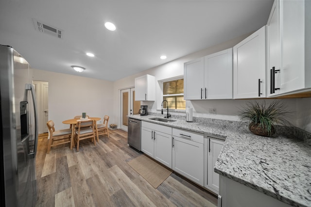 kitchen featuring light wood finished floors, visible vents, appliances with stainless steel finishes, white cabinetry, and a sink