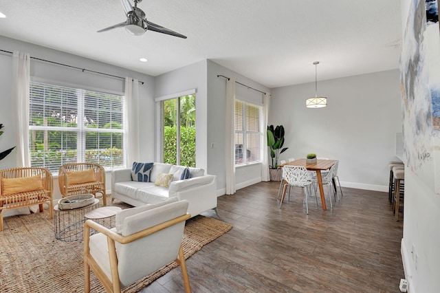 living area with dark wood finished floors, a textured ceiling, baseboards, and ceiling fan