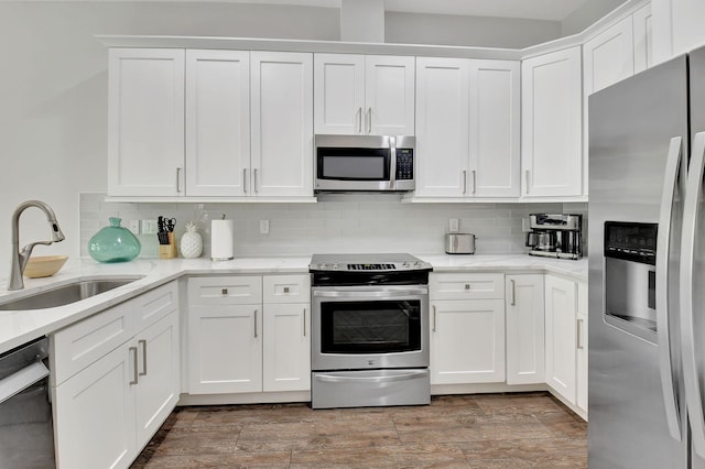 kitchen featuring backsplash, appliances with stainless steel finishes, white cabinets, and a sink