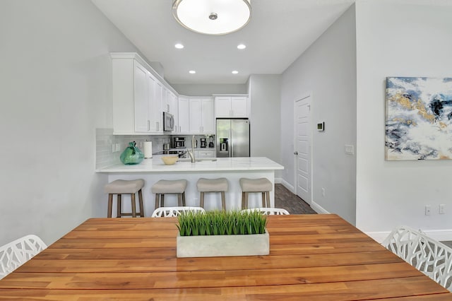 kitchen with white cabinets, decorative backsplash, a peninsula, stainless steel appliances, and light countertops