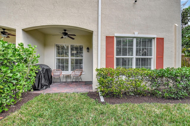 view of exterior entry featuring a patio area, a ceiling fan, and stucco siding