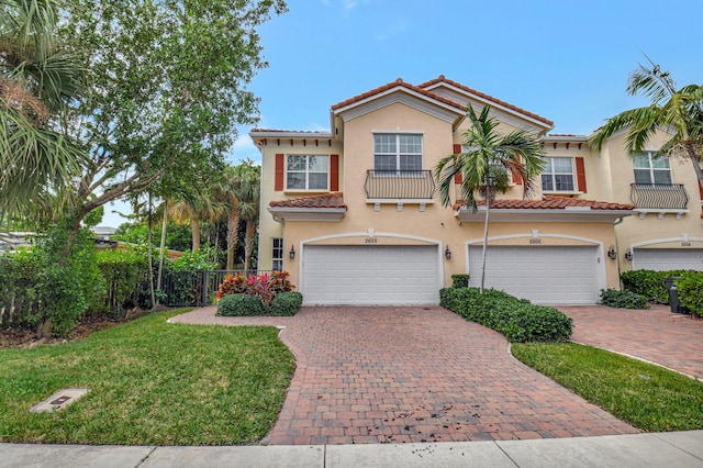 mediterranean / spanish-style home with a garage, a tile roof, decorative driveway, stucco siding, and a front yard