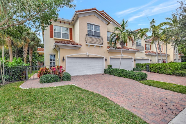 mediterranean / spanish-style home with a garage, decorative driveway, a tile roof, and stucco siding