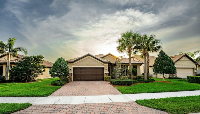 view of front of home with an attached garage, stucco siding, decorative driveway, and a front yard