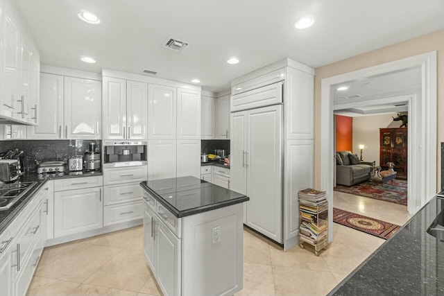 kitchen with paneled refrigerator, white cabinetry, a kitchen island, and light tile patterned flooring