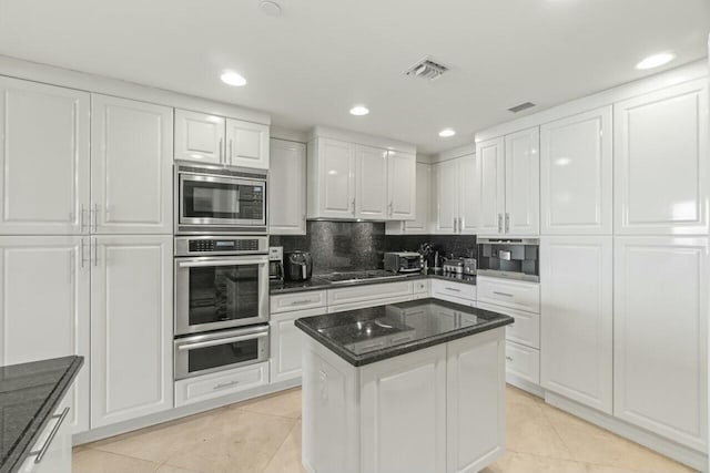 kitchen with a kitchen island, white cabinets, stainless steel appliances, and light tile patterned floors