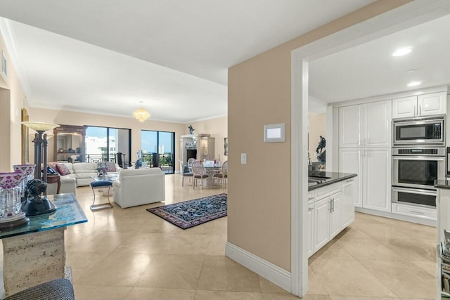 kitchen featuring crown molding, white cabinets, stainless steel microwave, and light tile patterned flooring