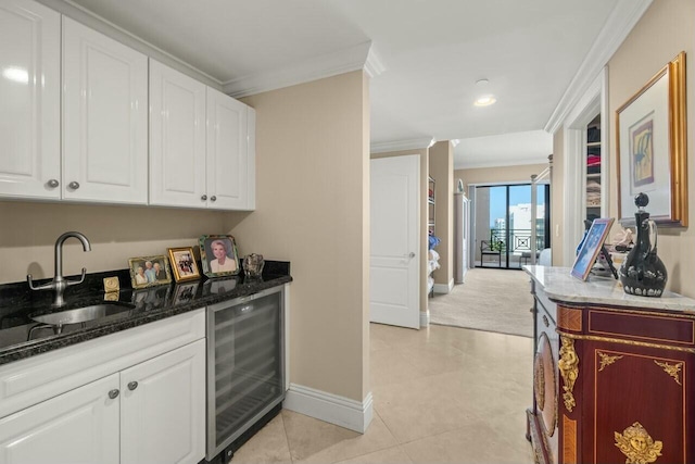 kitchen featuring sink, light tile patterned flooring, wine cooler, crown molding, and white cabinets