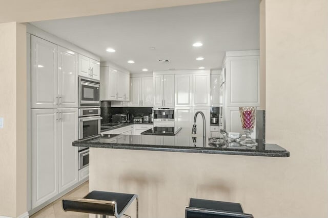 kitchen featuring appliances with stainless steel finishes, white cabinetry, a breakfast bar, and kitchen peninsula