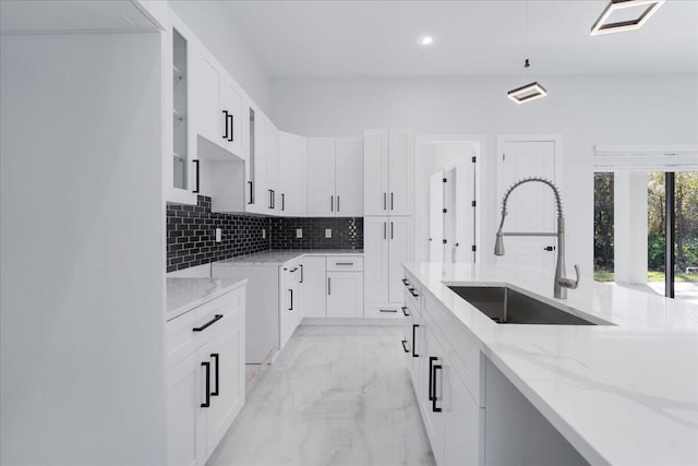 kitchen featuring decorative backsplash, sink, light stone countertops, and white cabinets