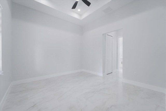 spare room with a tray ceiling and ceiling fan