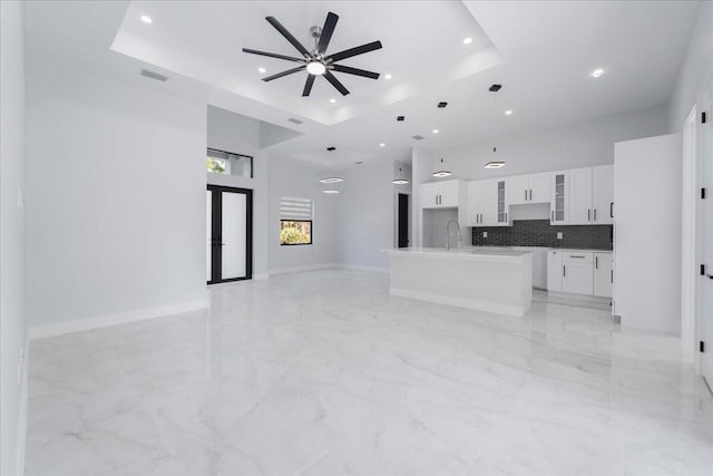 living room with ceiling fan, sink, a high ceiling, and a raised ceiling