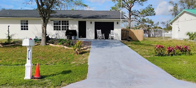 view of front of home with a garage, driveway, a front yard, and fence