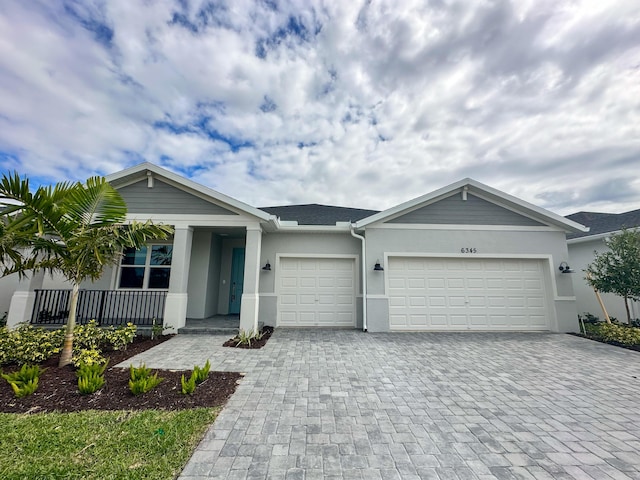 ranch-style home featuring a garage, roof with shingles, decorative driveway, and stucco siding