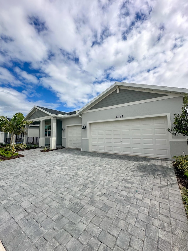 view of front facade with a garage, decorative driveway, and stucco siding