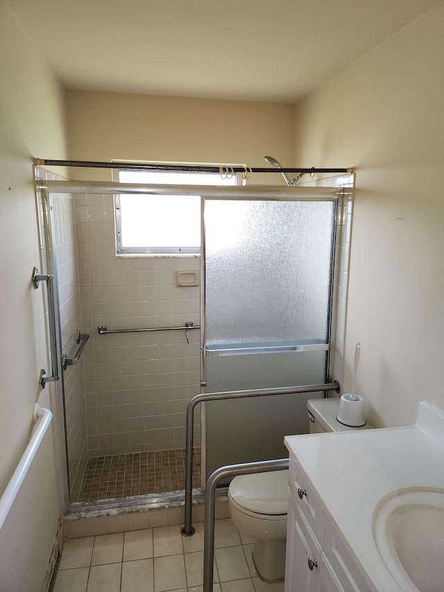 bathroom featuring toilet, tile patterned floors, an enclosed shower, and vanity