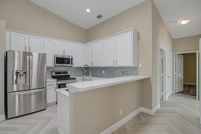 kitchen with white cabinetry, stainless steel appliances, light parquet floors, and kitchen peninsula