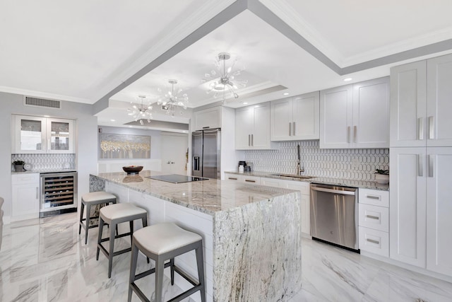 kitchen with sink, beverage cooler, a kitchen island, stainless steel appliances, and white cabinets