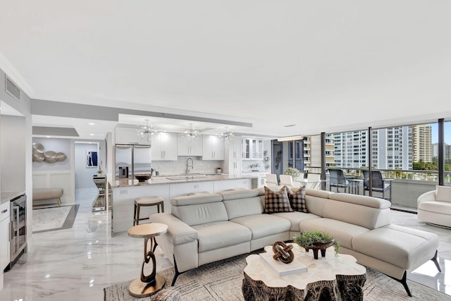 living room featuring an inviting chandelier, sink, beverage cooler, and ornamental molding