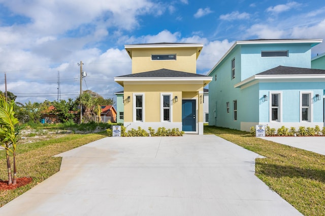 view of front facade with stucco siding and a front yard