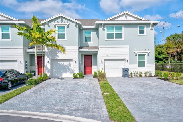 view of front of property with driveway, a garage, fence, and stucco siding