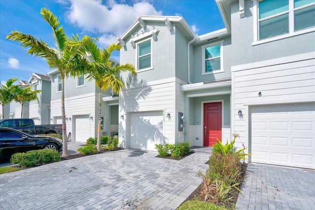 view of front of house with an attached garage, decorative driveway, and stucco siding