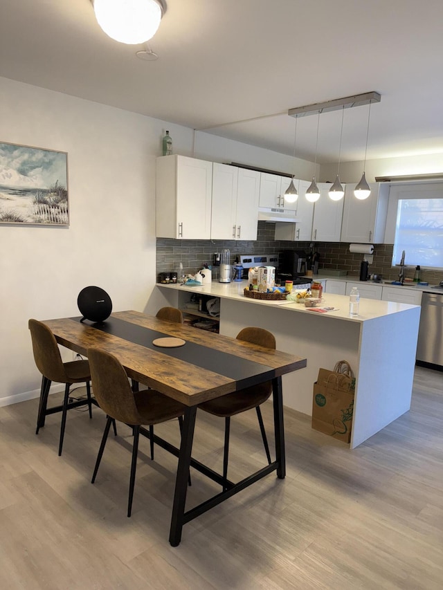 kitchen featuring sink, stainless steel appliances, white cabinets, hanging light fixtures, and decorative backsplash