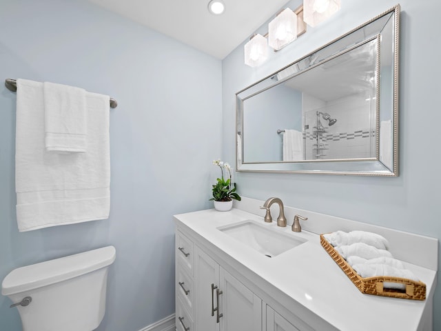 bathroom with vanity, a tile shower, and toilet