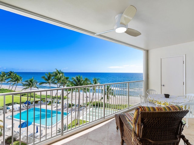 balcony with ceiling fan, a water view, and a view of the beach