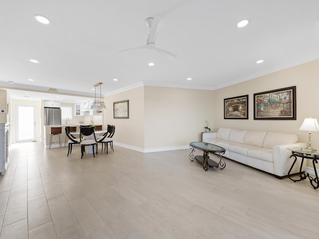 living room with light hardwood / wood-style flooring, ceiling fan, and ornamental molding