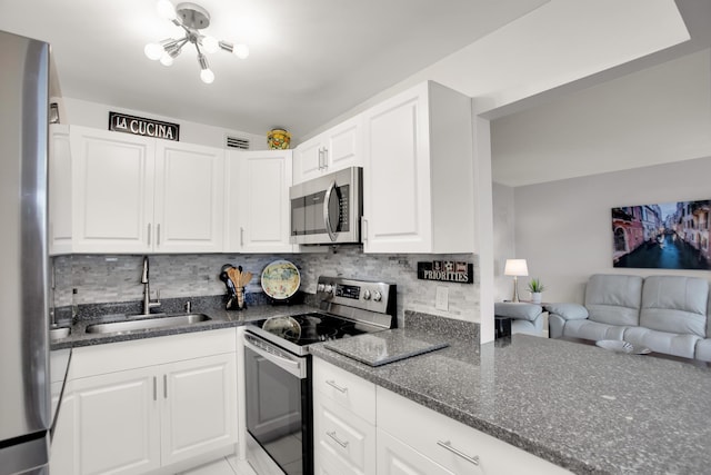 kitchen featuring backsplash, stainless steel appliances, a sink, and open floor plan