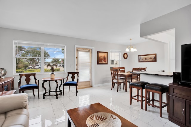 living room featuring marble finish floor, baseboards, and an inviting chandelier