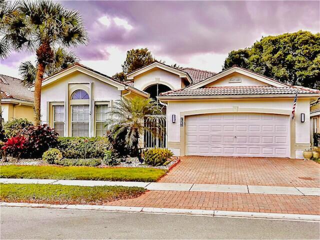 view of front of property with an attached garage, a tile roof, decorative driveway, and stucco siding